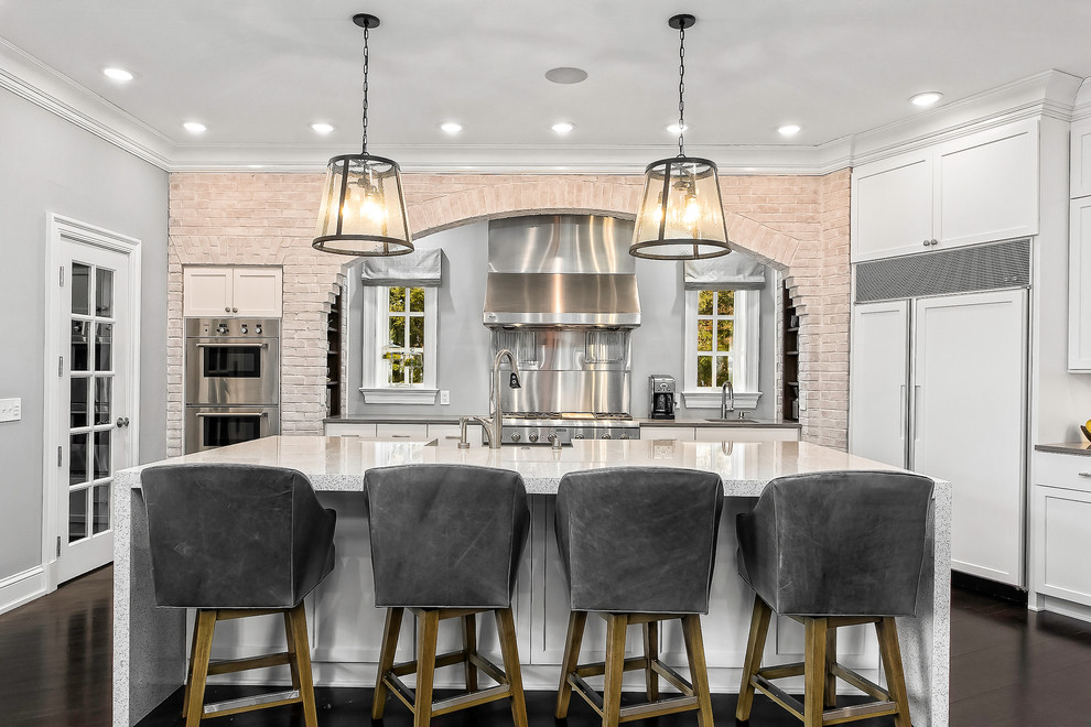 Immagine di un cucina con isola centrale chic con ante in stile shaker, ante bianche, paraspruzzi grigio, pavimento marrone e elettrodomestici da incasso