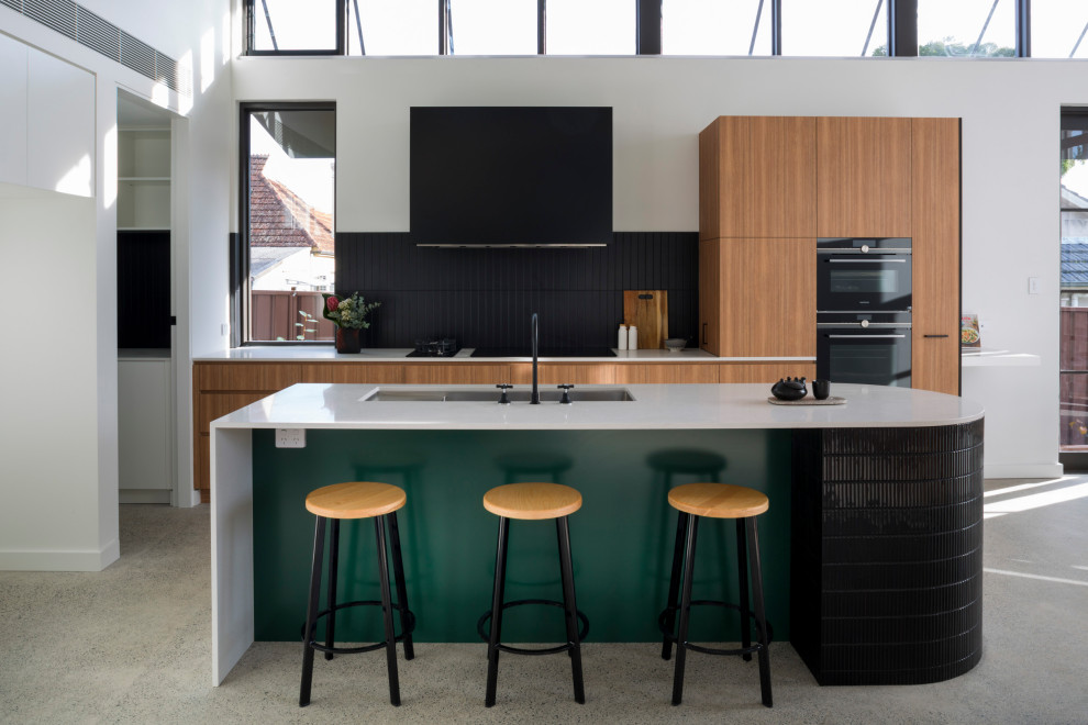 Cette image montre une cuisine ouverte linéaire design en bois brun de taille moyenne avec une crédence noire, une crédence en céramique, îlot et un plan de travail blanc.