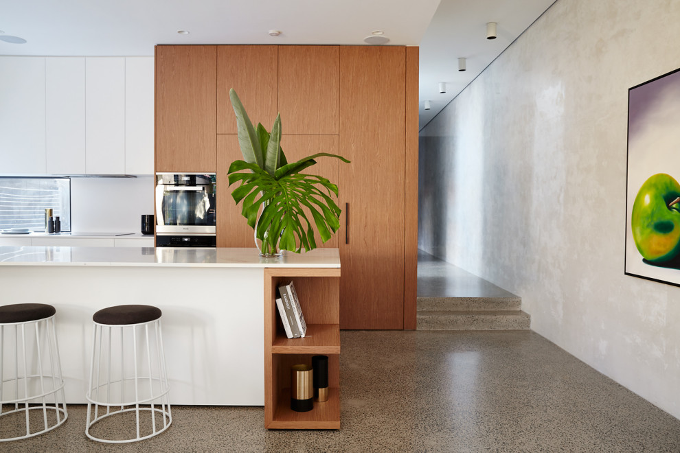 Zweizeilige Moderne Küche mit flächenbündigen Schrankfronten, hellbraunen Holzschränken, Betonboden, Kücheninsel, grauem Boden und weißer Arbeitsplatte in Sydney