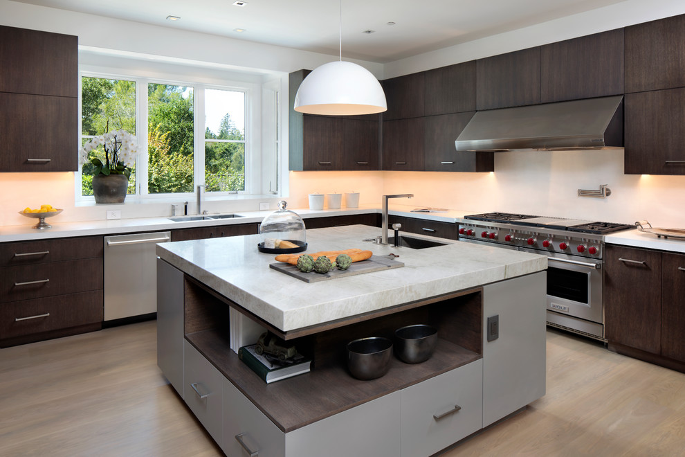 Traditional l-shaped kitchen in San Francisco with a double-bowl sink, flat-panel cabinets, dark wood cabinets, stainless steel appliances, light hardwood flooring, an island and beige floors.