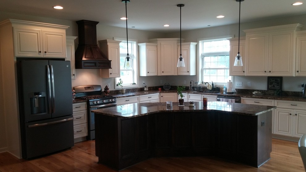 Immagine di una grande cucina classica con lavello sottopiano, ante con bugna sagomata, ante bianche, top in granito, elettrodomestici neri, parquet scuro e pavimento marrone