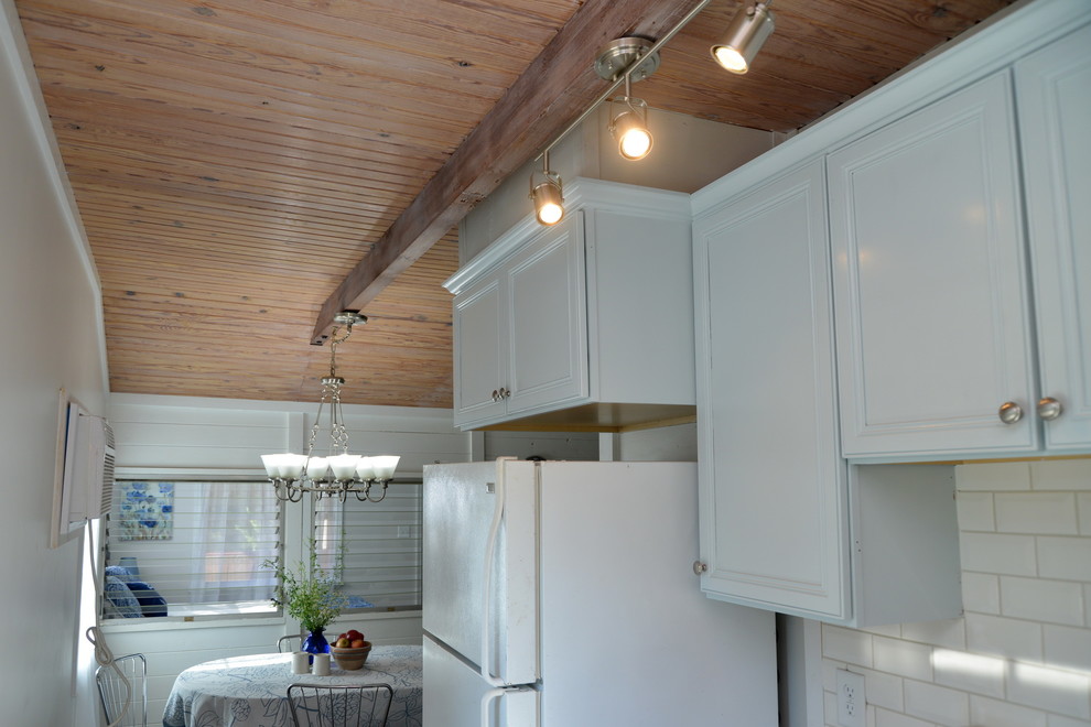 Inspiration för ett litet lantligt grå grått kök, med en nedsänkt diskho, luckor med infälld panel, blå skåp, laminatbänkskiva, vitt stänkskydd, stänkskydd i tunnelbanekakel, vita vitvaror, vinylgolv och brunt golv