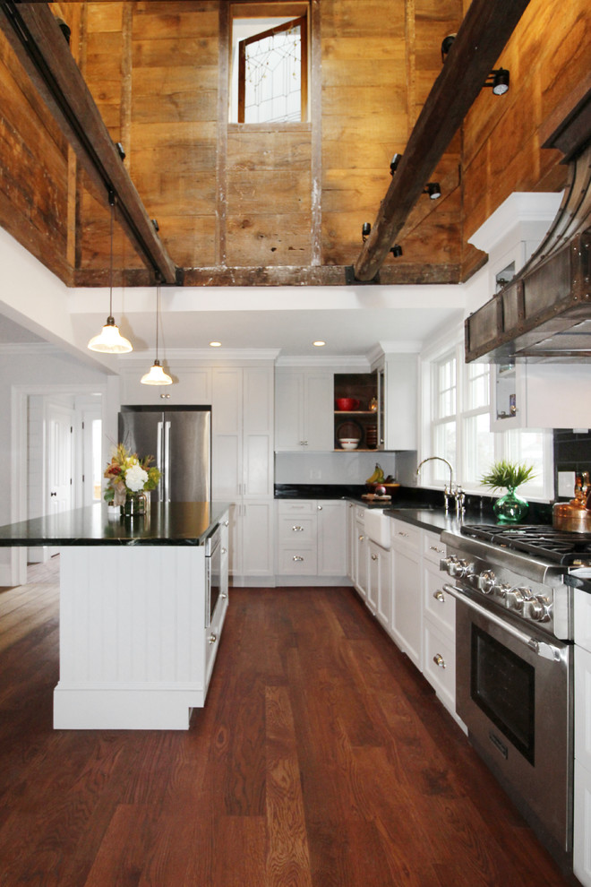 Idéer för att renovera ett mellanstort lantligt kök, med en rustik diskho, skåp i shakerstil, vita skåp, bänkskiva i täljsten, svart stänkskydd, stänkskydd i porslinskakel, rostfria vitvaror, mellanmörkt trägolv, en köksö och brunt golv