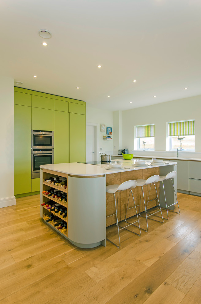 Offene, Geräumige Moderne Küche mit flächenbündigen Schrankfronten, Küchengeräten aus Edelstahl, braunem Holzboden und Kücheninsel in Cornwall