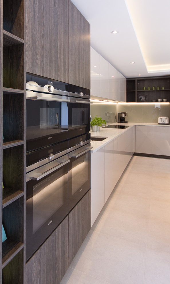 Design ideas for a medium sized modern l-shaped open plan kitchen in London with an integrated sink, flat-panel cabinets, beige cabinets, composite countertops, beige splashback, glass sheet splashback, stainless steel appliances and an island.