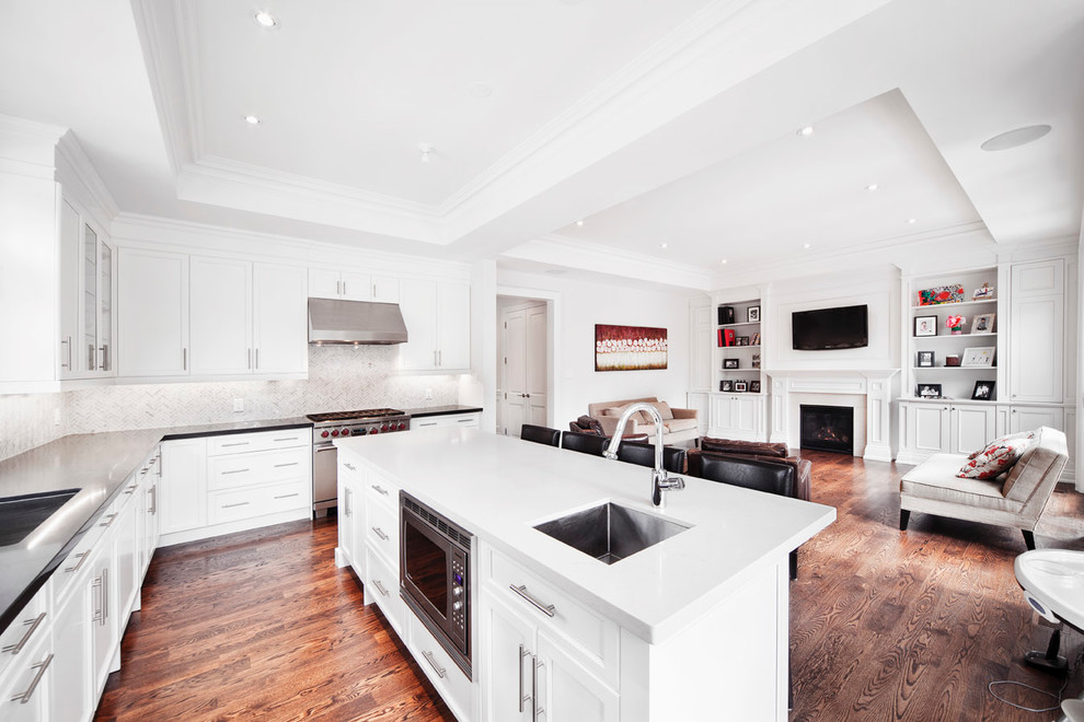 Transitional open concept kitchen photo in Toronto with recessed-panel cabinets, stainless steel appliances, a single-bowl sink, white backsplash and stone tile backsplash