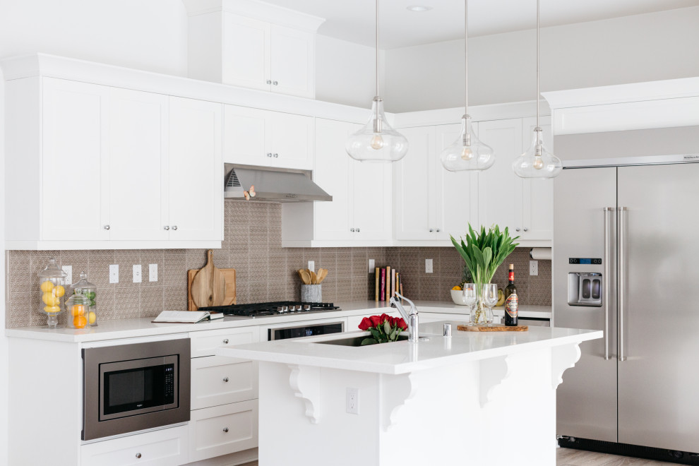 Immagine di una cucina classica con lavello sottopiano, ante in stile shaker, ante bianche, paraspruzzi marrone, elettrodomestici in acciaio inossidabile, pavimento grigio e top bianco