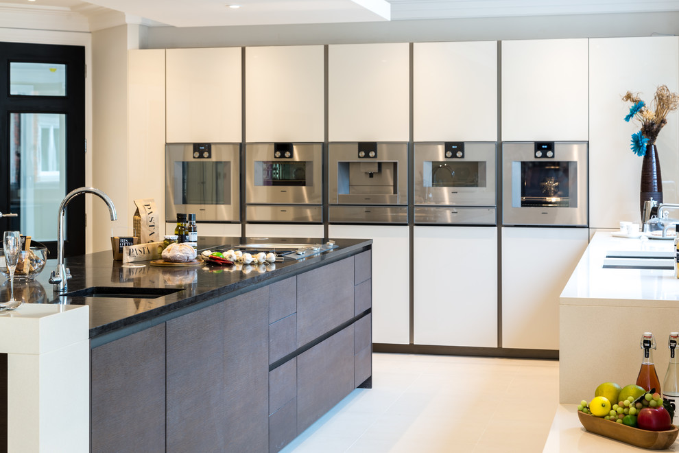 Large contemporary u-shaped kitchen in Surrey with a built-in sink, flat-panel cabinets, beige cabinets, composite countertops, stainless steel appliances and an island.