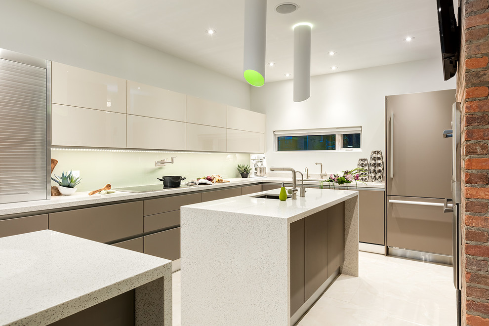 Geschlossene Moderne Küche in L-Form mit Unterbauwaschbecken, flächenbündigen Schrankfronten, beigen Schränken, Glasrückwand, Elektrogeräten mit Frontblende und zwei Kücheninseln in Calgary