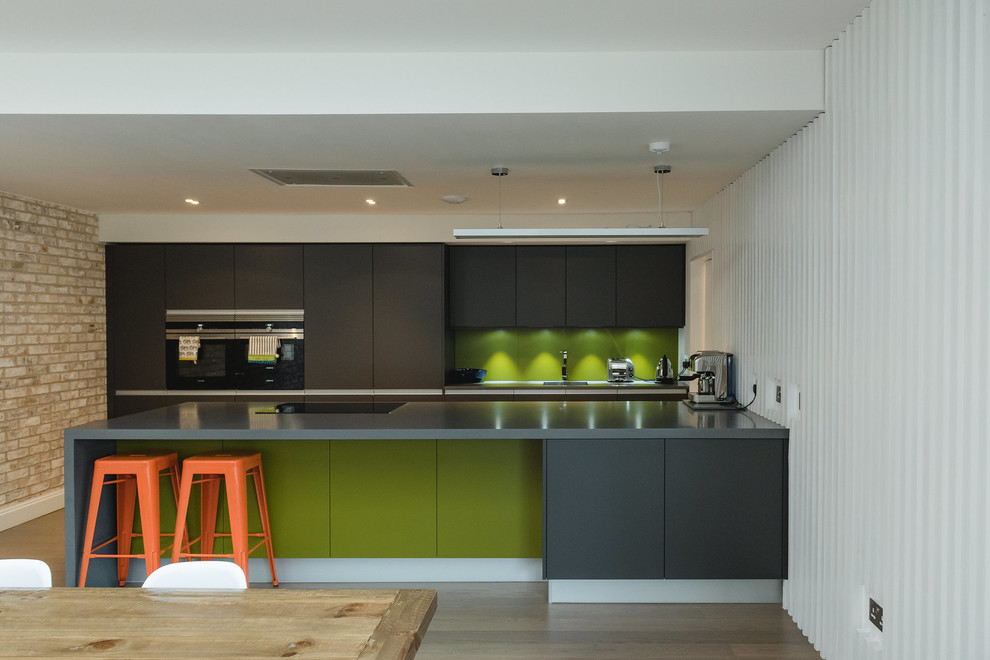 Medium sized contemporary galley kitchen in Glasgow with a submerged sink, flat-panel cabinets, black cabinets, granite worktops, green splashback, stainless steel appliances and black worktops.