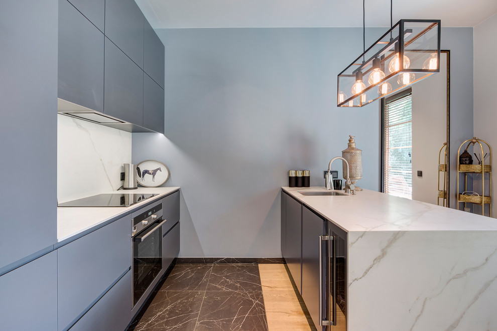 Réalisation d'une petite cuisine parallèle design avec un placard à porte plane, des portes de placard bleues, plan de travail en marbre, une crédence blanche et un sol marron.