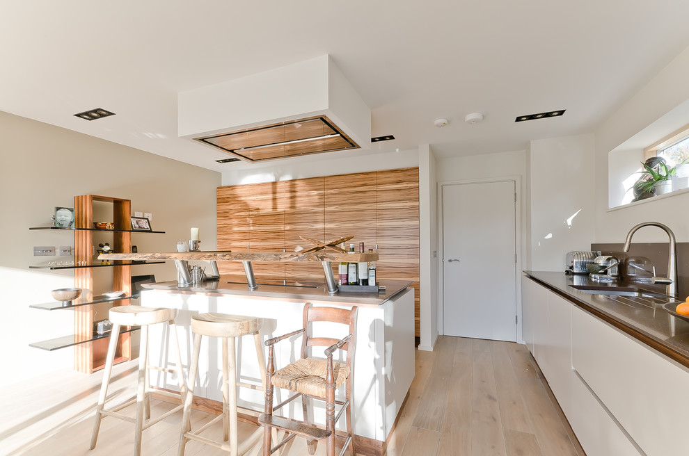 Skandinavische Küchenbar mit Unterbauwaschbecken, flächenbündigen Schrankfronten, weißen Schränken, hellem Holzboden und Kücheninsel in Surrey