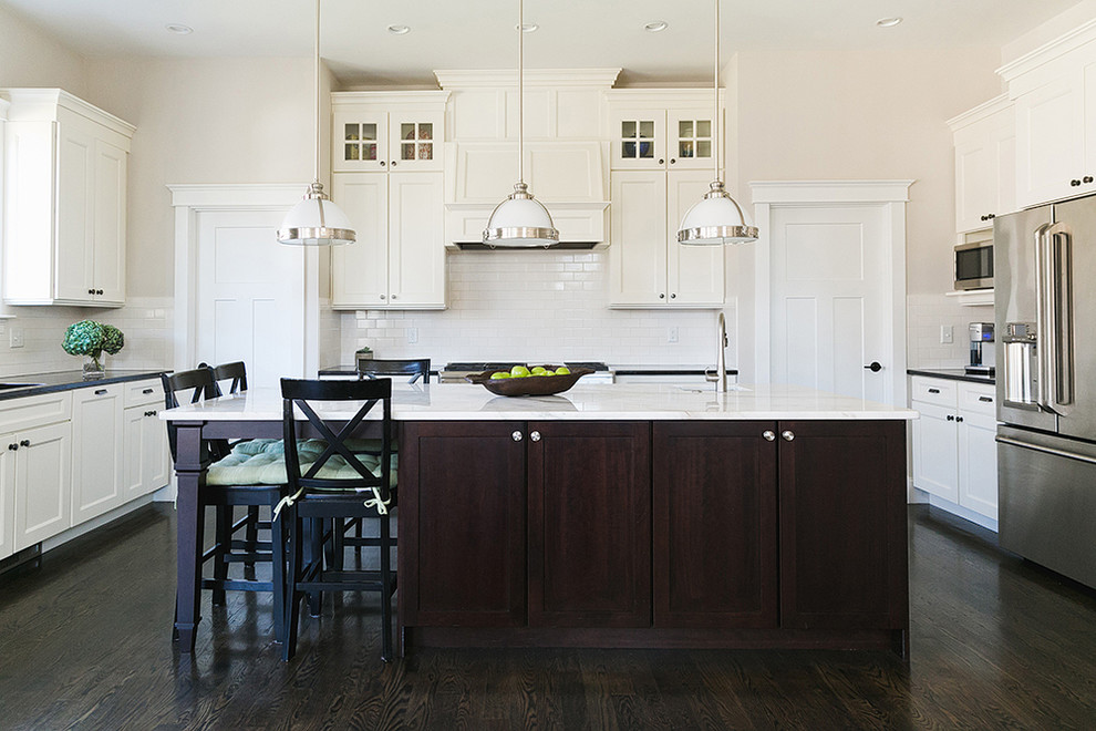 Design ideas for a classic u-shaped kitchen in Boston with recessed-panel cabinets, white cabinets, white splashback, metro tiled splashback, stainless steel appliances, dark hardwood flooring and an island.