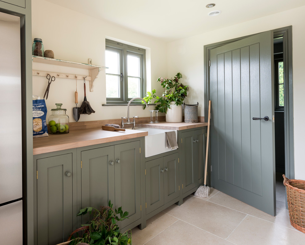 Inspiration for a farmhouse single-wall kitchen in West Midlands with a belfast sink, shaker cabinets, green cabinets, wood worktops and stainless steel appliances.