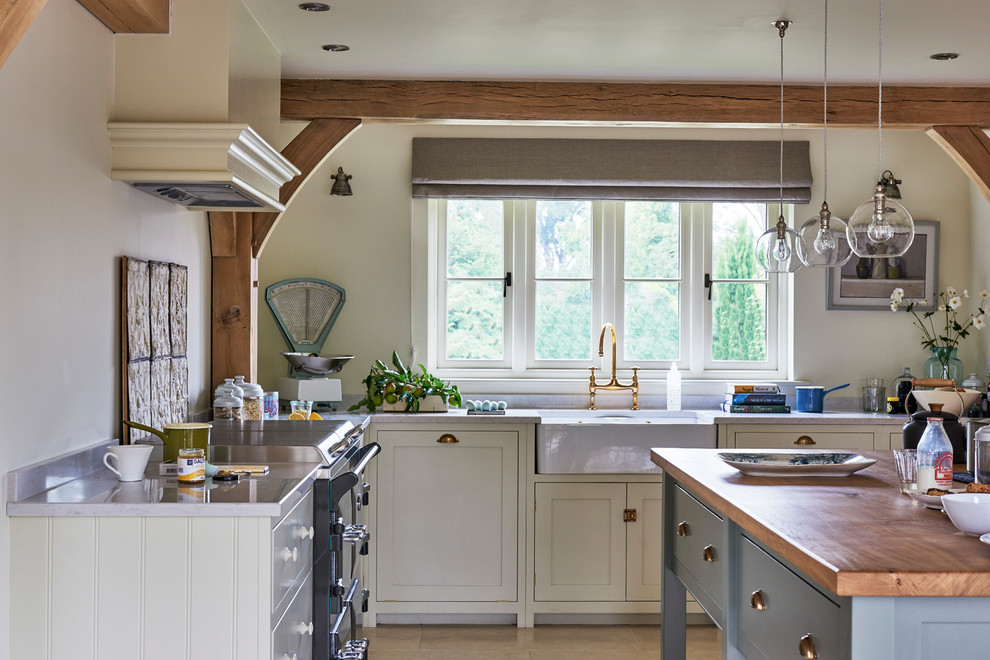 This is an example of a medium sized farmhouse l-shaped kitchen/diner in West Midlands with a belfast sink, shaker cabinets, quartz worktops, coloured appliances, limestone flooring and an island.
