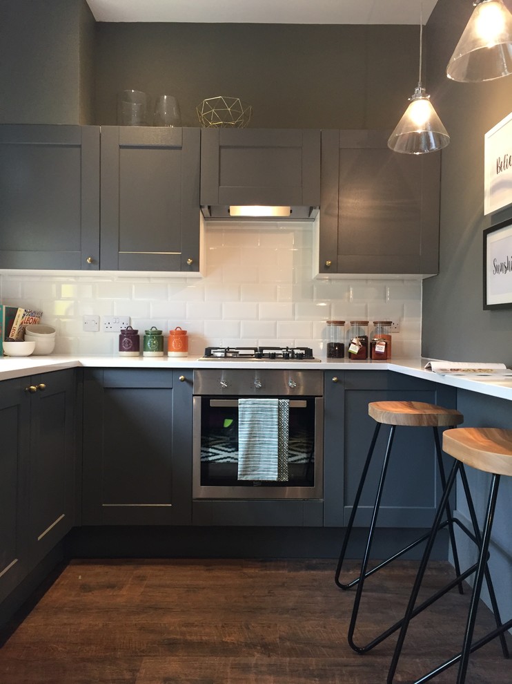 Photo of a small contemporary u-shaped open plan kitchen in Other with a built-in sink, raised-panel cabinets, grey cabinets, quartz worktops, white splashback, ceramic splashback, integrated appliances, laminate floors, no island, brown floors and white worktops.