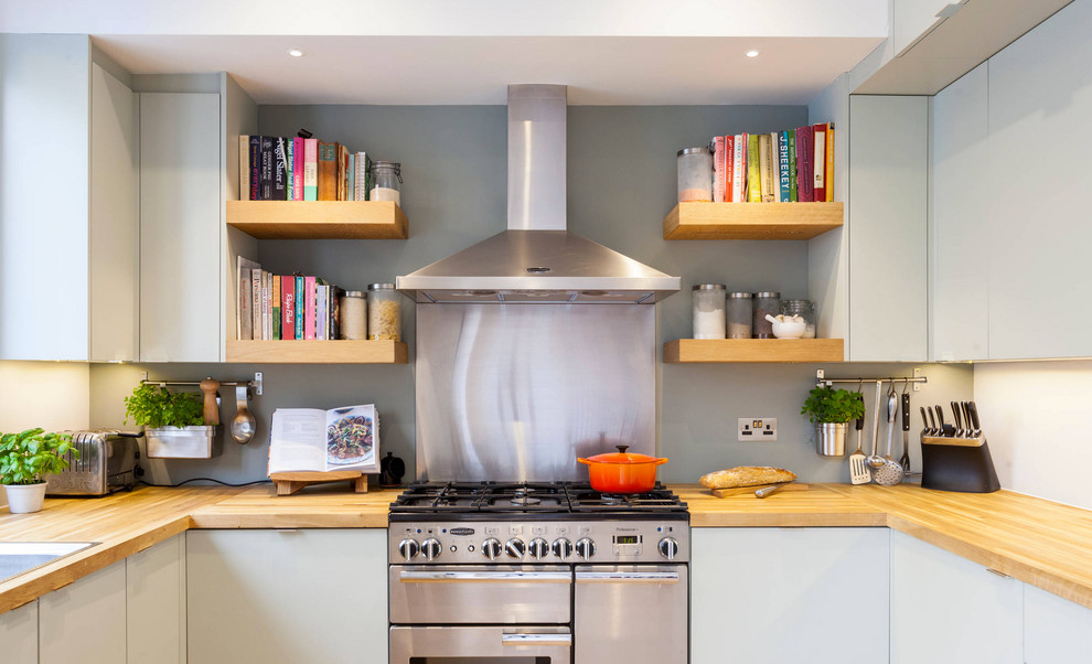Photo of a medium sized contemporary u-shaped kitchen in London with a built-in sink, flat-panel cabinets, grey cabinets, wood worktops, stainless steel appliances and no island.
