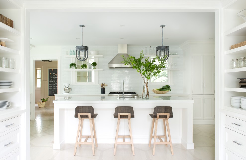 Danish kitchen photo in New York with recessed-panel cabinets, white cabinets, white backsplash, stainless steel appliances and an island