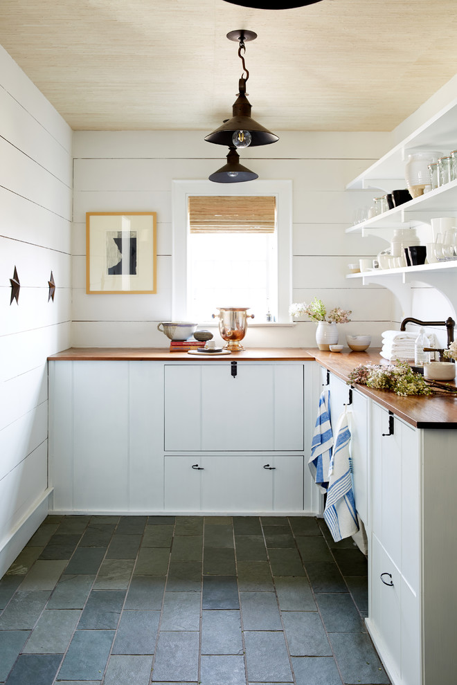 Foto de cocinas en L de estilo de casa de campo sin isla con armarios con paneles lisos, puertas de armario blancas, encimera de madera y suelo gris