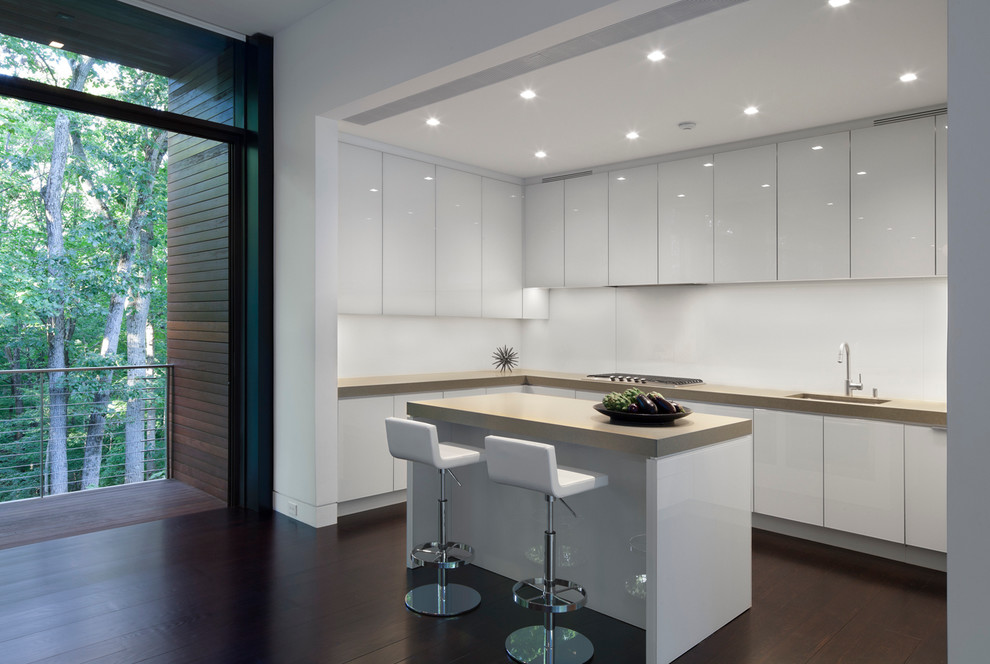 Example of a large minimalist u-shaped dark wood floor open concept kitchen design in New York with flat-panel cabinets, white cabinets, white backsplash, stainless steel appliances, an island and an undermount sink