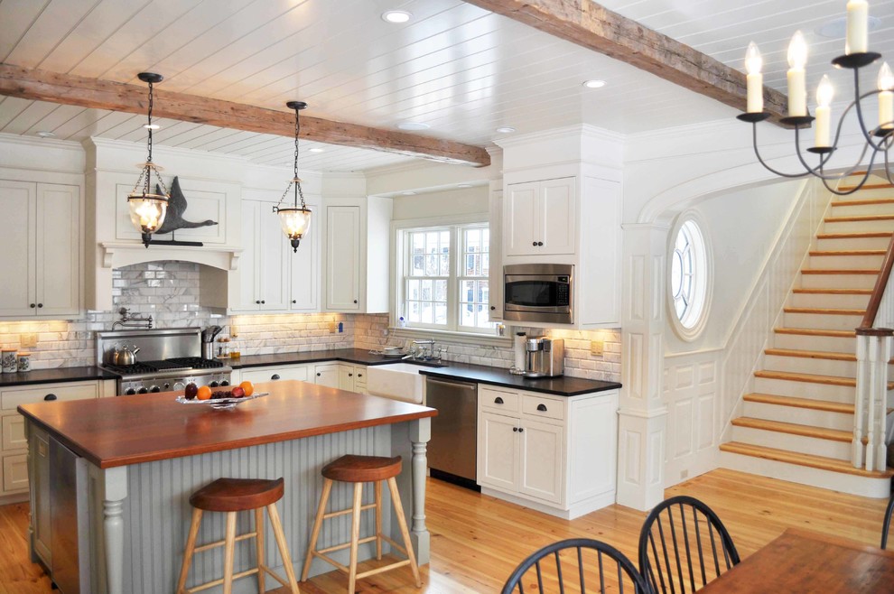 Kitchen - mid-sized traditional u-shaped light wood floor and brown floor kitchen idea in Boston with a farmhouse sink, shaker cabinets, white cabinets, wood countertops, gray backsplash, subway tile backsplash, stainless steel appliances and an island