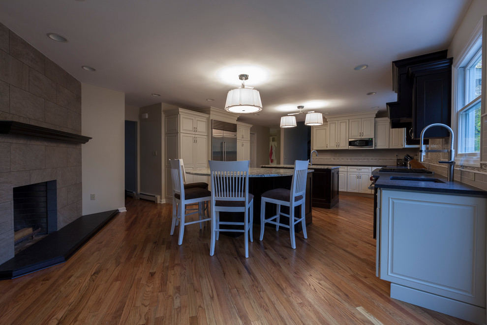Example of a huge transitional l-shaped light wood floor eat-in kitchen design in Bridgeport with an undermount sink, flat-panel cabinets, white cabinets, granite countertops, white backsplash, ceramic backsplash, stainless steel appliances and two islands