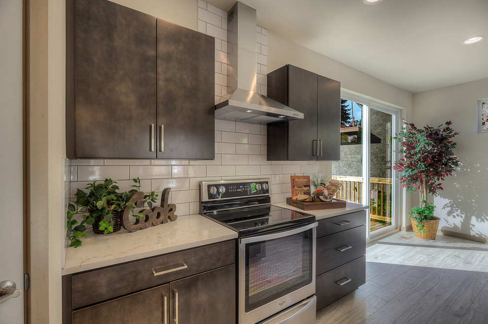 Eat-in kitchen - large contemporary single-wall light wood floor and gray floor eat-in kitchen idea in Seattle with an undermount sink, flat-panel cabinets, brown cabinets, granite countertops, white backsplash, subway tile backsplash, stainless steel appliances and an island