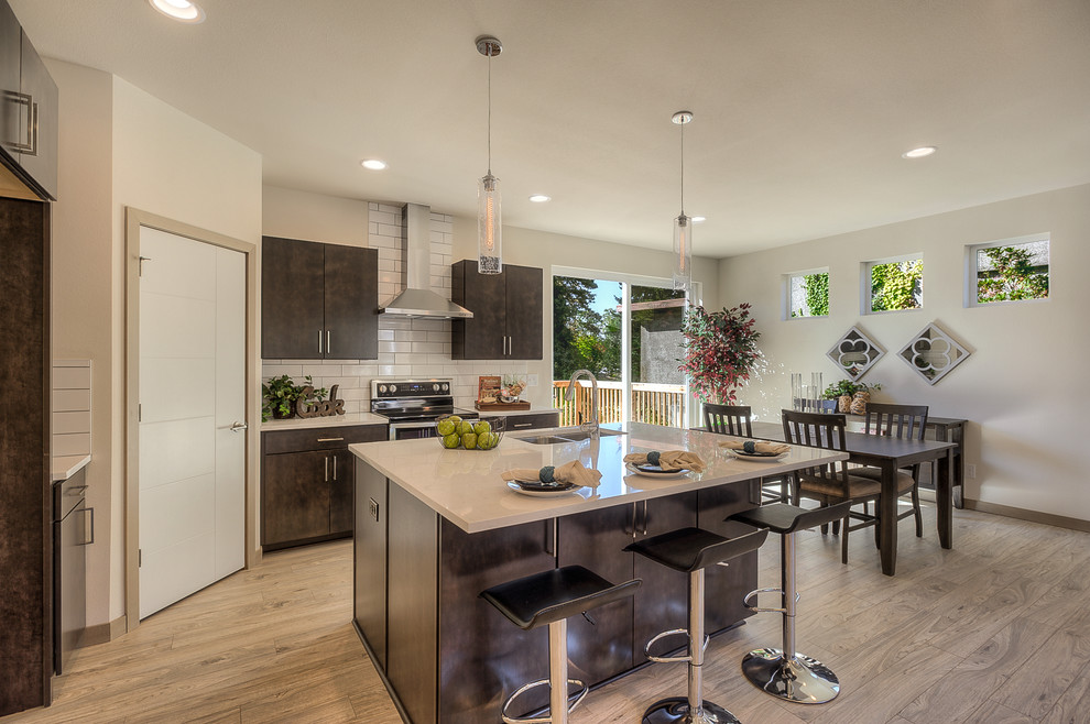 Large contemporary galley kitchen/diner in Seattle with a submerged sink, flat-panel cabinets, brown cabinets, granite worktops, white splashback, metro tiled splashback, stainless steel appliances, light hardwood flooring, an island and grey floors.