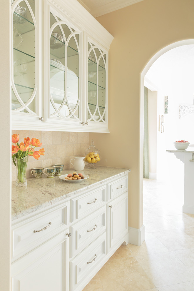 Cette photo montre une grande arrière-cuisine méditerranéenne avec un placard à porte vitrée, des portes de placard blanches, un plan de travail en granite, une crédence beige, une crédence en carrelage de pierre et un sol en travertin.