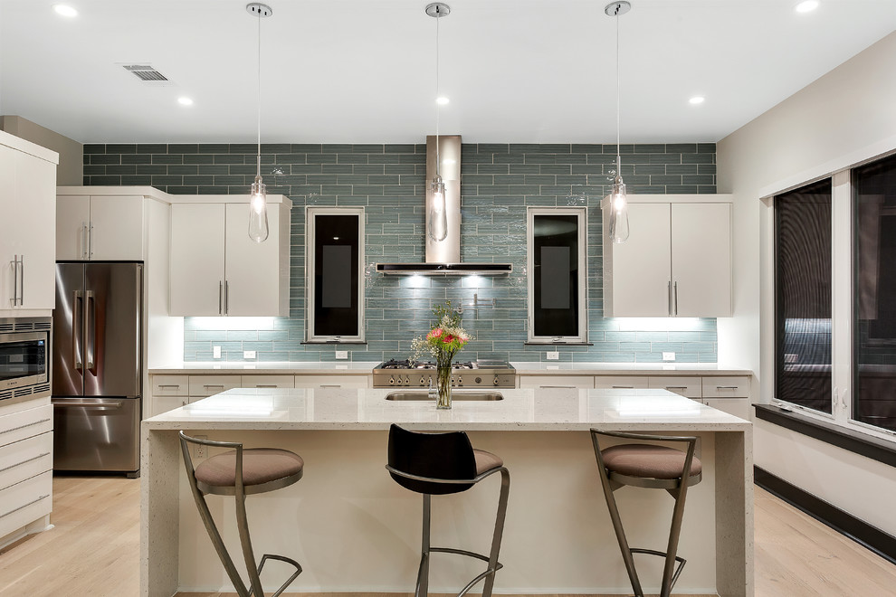 Example of a trendy kitchen design in Austin with an undermount sink, flat-panel cabinets, white cabinets, gray backsplash, subway tile backsplash, stainless steel appliances and an island