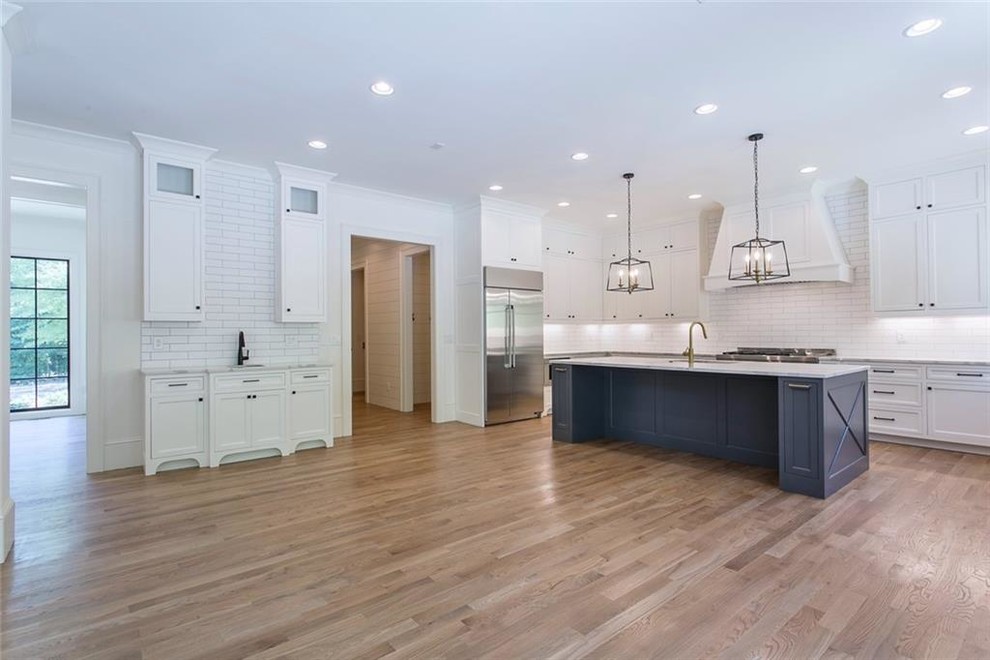 Example of a large transitional galley light wood floor and gray floor eat-in kitchen design in Atlanta with a single-bowl sink, recessed-panel cabinets, gray cabinets, quartzite countertops, white backsplash, ceramic backsplash, stainless steel appliances, an island and gray countertops