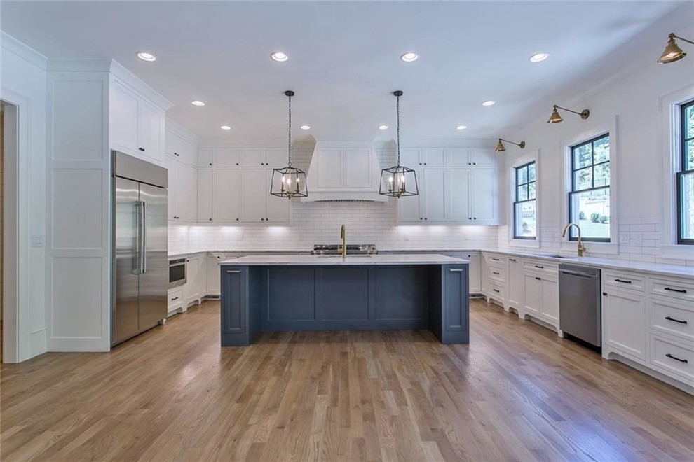 Photo of a large traditional galley kitchen/diner in Atlanta with a single-bowl sink, recessed-panel cabinets, grey cabinets, quartz worktops, white splashback, ceramic splashback, stainless steel appliances, light hardwood flooring, an island, grey floors and grey worktops.