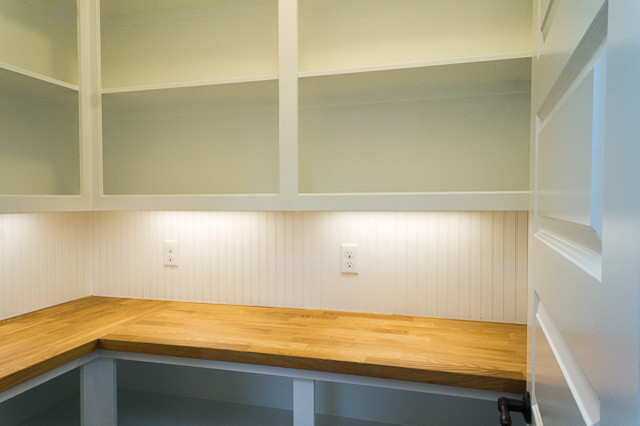 Amerikansk inredning av ett mellanstort kök, med en undermonterad diskho, luckor med infälld panel, vita skåp, bänkskiva i kvarts, vitt stänkskydd, stänkskydd i tunnelbanekakel, rostfria vitvaror, mellanmörkt trägolv och en köksö