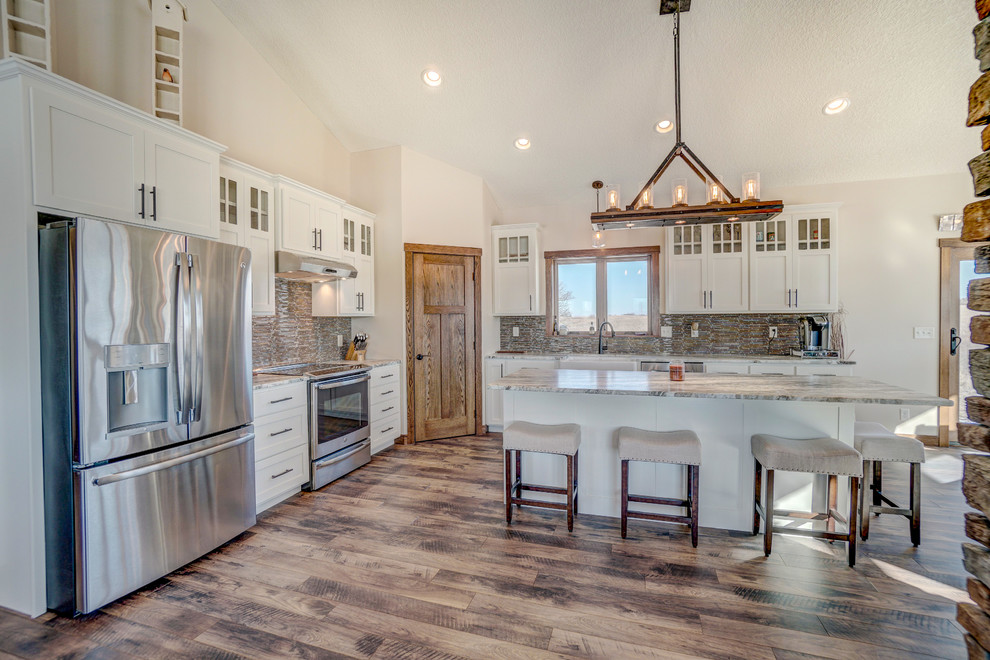 Large mountain style brown floor open concept kitchen photo in Minneapolis with a farmhouse sink, glass-front cabinets, white cabinets, brown backsplash, stainless steel appliances and an island