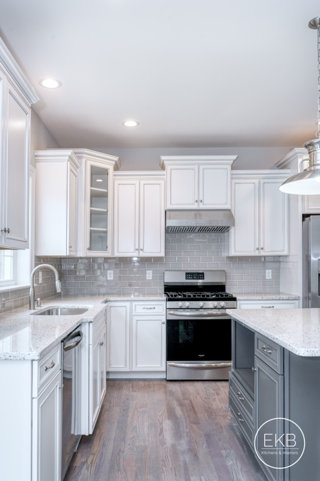 Idéer för att renovera ett stort vintage vit vitt kök, med en undermonterad diskho, luckor med infälld panel, vita skåp, bänkskiva i kvarts, grått stänkskydd, stänkskydd i glaskakel, rostfria vitvaror, ljust trägolv, en köksö och brunt golv