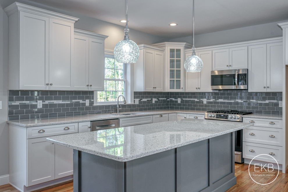 Exempel på ett stort flerfärgad flerfärgat kök, med en undermonterad diskho, skåp i shakerstil, vita skåp, bänkskiva i kvarts, grått stänkskydd, stänkskydd i keramik, rostfria vitvaror, ljust trägolv, en köksö och brunt golv