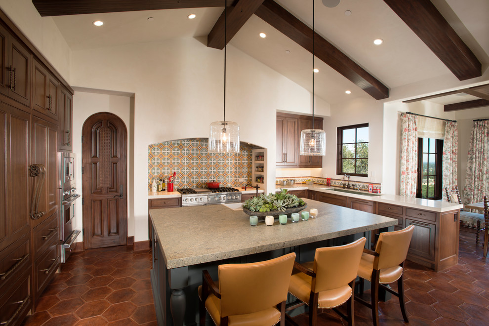 Large elegant u-shaped terra-cotta tile eat-in kitchen photo in San Francisco with an undermount sink, recessed-panel cabinets, medium tone wood cabinets, solid surface countertops, white backsplash, mosaic tile backsplash, stainless steel appliances and an island