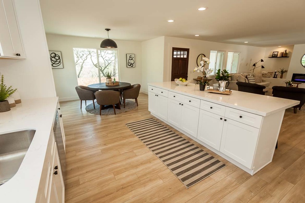 Exempel på ett mellanstort modernt vit vitt kök, med en undermonterad diskho, skåp i shakerstil, vita skåp, bänkskiva i kvarts, vitt stänkskydd, stänkskydd i tunnelbanekakel, rostfria vitvaror, ljust trägolv, en köksö och beiget golv