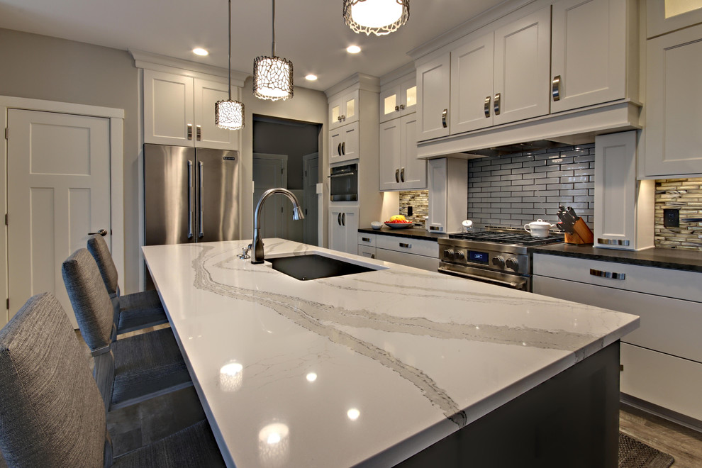Inredning av ett modernt mellanstort kök, med en integrerad diskho, luckor med infälld panel, vita skåp, bänkskiva i kvarts, flerfärgad stänkskydd, stänkskydd i keramik, rostfria vitvaror, vinylgolv, en köksö och flerfärgat golv