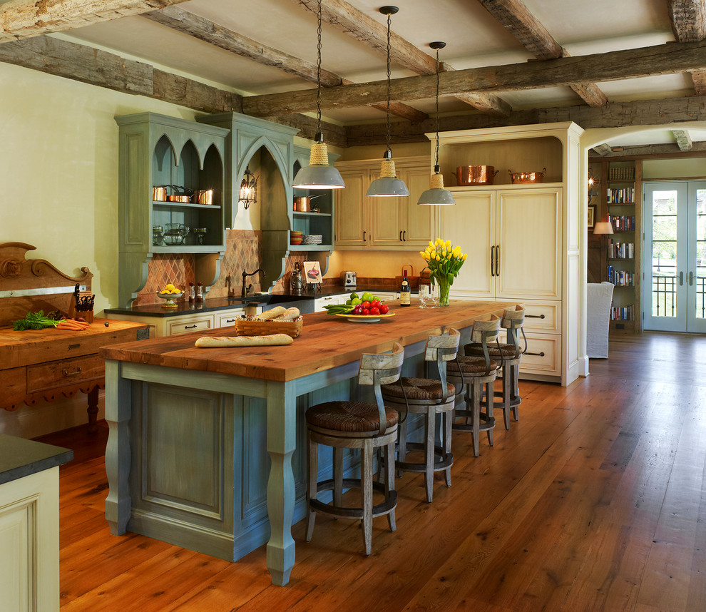 Inspiration for a mediterranean dark wood floor eat-in kitchen remodel in DC Metro with a farmhouse sink, recessed-panel cabinets, distressed cabinets, wood countertops, paneled appliances and an island