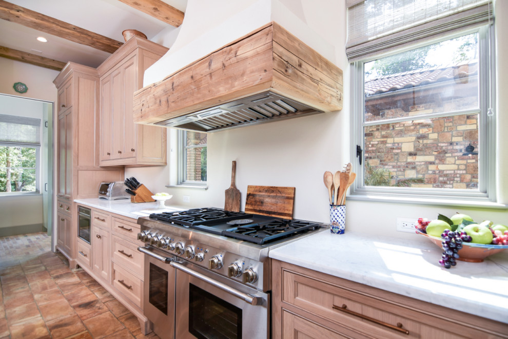 Cette image montre une cuisine ouverte linéaire et encastrable méditerranéenne en bois brun de taille moyenne avec un évier de ferme, un placard à porte affleurante, un plan de travail en bois, tomettes au sol, îlot, un sol multicolore et un plan de travail multicolore.