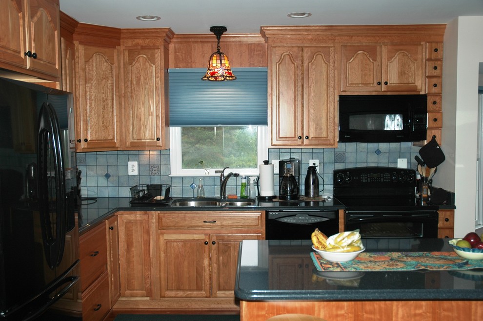 Bild på ett mellanstort funkis kök, med en undermonterad diskho, skåp i ljust trä, svarta vitvaror och en köksö