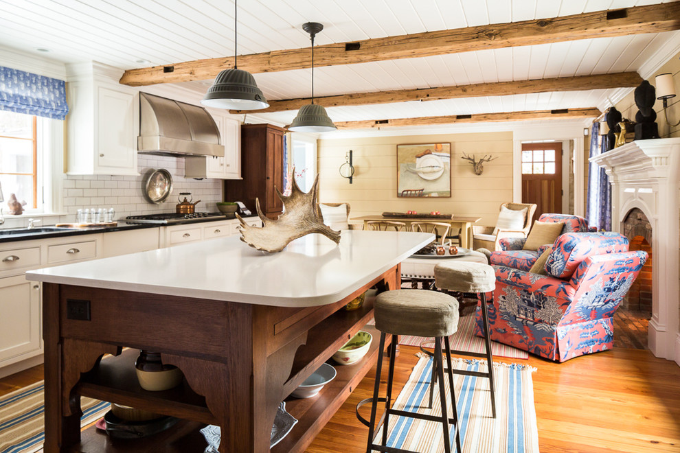 Design ideas for a farmhouse open plan kitchen in Portland Maine with a submerged sink, beaded cabinets, white cabinets, white splashback, metro tiled splashback, medium hardwood flooring and an island.