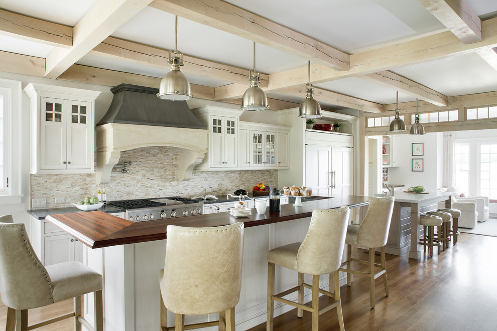 Lantlig inredning av ett grå grått kök, med flera köksöar, skåp i shakerstil, vita skåp, beige stänkskydd, stänkskydd i stickkakel, integrerade vitvaror, mellanmörkt trägolv och brunt golv