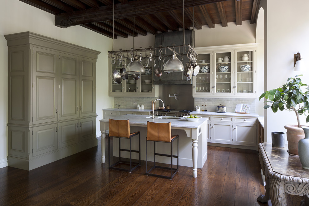 Foto på ett stort vintage kök, med en enkel diskho, luckor med infälld panel, vita skåp, marmorbänkskiva, stänkskydd med metallisk yta, mörkt trägolv och en köksö
