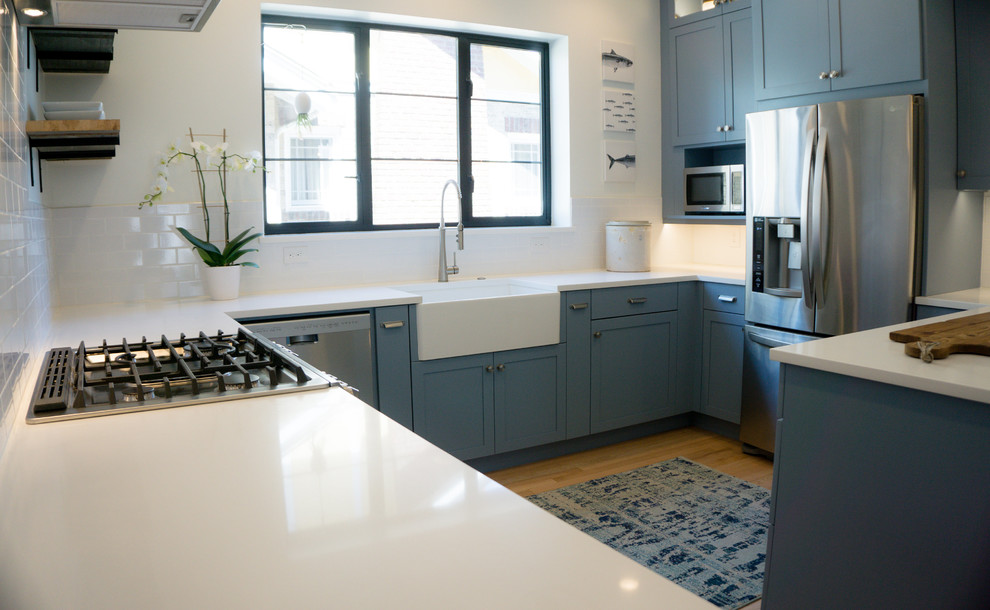 Photo of a medium sized traditional kitchen in Denver with a submerged sink, shaker cabinets, blue cabinets, engineered stone countertops, white splashback, metro tiled splashback and stainless steel appliances.