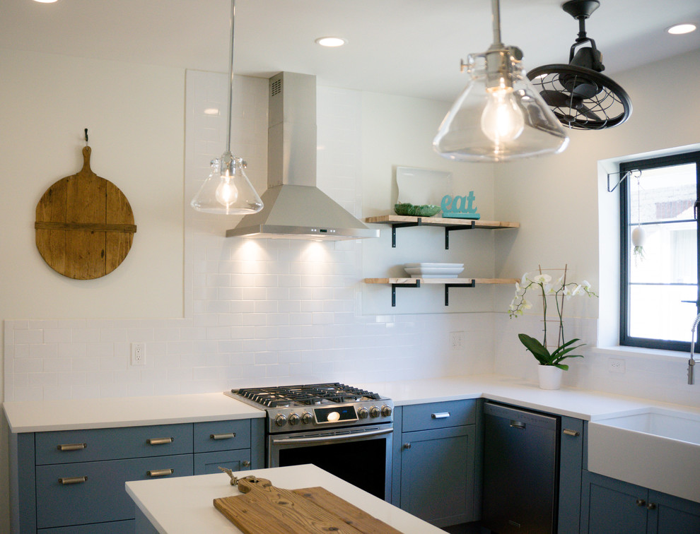Amerikansk inredning av ett mellanstort kök, med en undermonterad diskho, skåp i shakerstil, blå skåp, bänkskiva i kvarts, vitt stänkskydd, stänkskydd i tunnelbanekakel och rostfria vitvaror