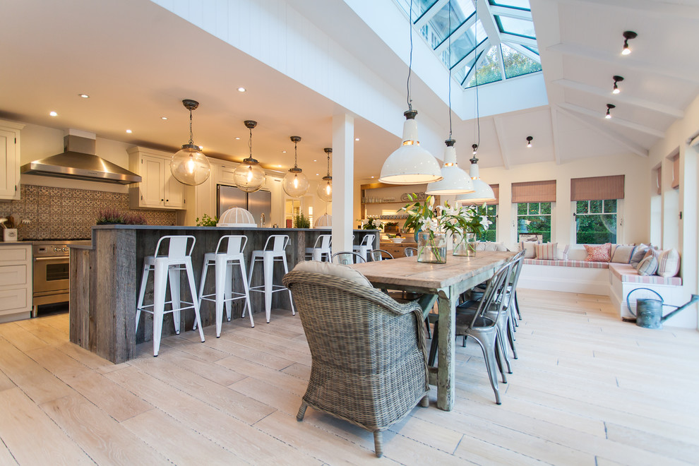 This is an example of a large nautical kitchen/diner in Sussex with painted wood flooring, a belfast sink, shaker cabinets, white cabinets, composite countertops, grey splashback, ceramic splashback, stainless steel appliances and an island.