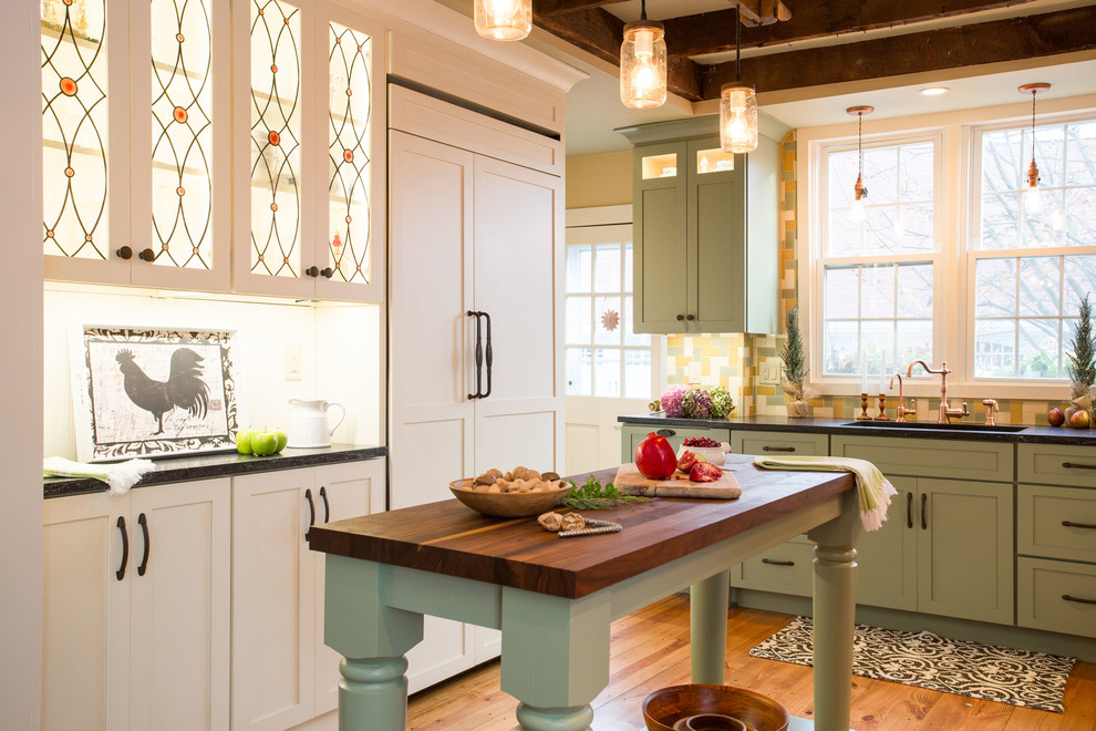 Klassisk inredning av ett stort kök, med en enkel diskho, skåp i shakerstil, gröna skåp, granitbänkskiva, flerfärgad stänkskydd, stänkskydd i glaskakel, integrerade vitvaror, mellanmörkt trägolv, flera köksöar och beiget golv