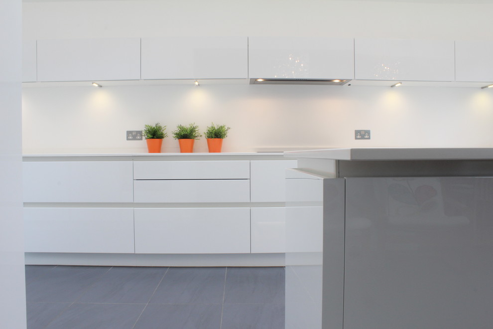 Photo of a medium sized modern kitchen/diner in Hertfordshire with a submerged sink, flat-panel cabinets, white cabinets, engineered stone countertops, stainless steel appliances, porcelain flooring and an island.